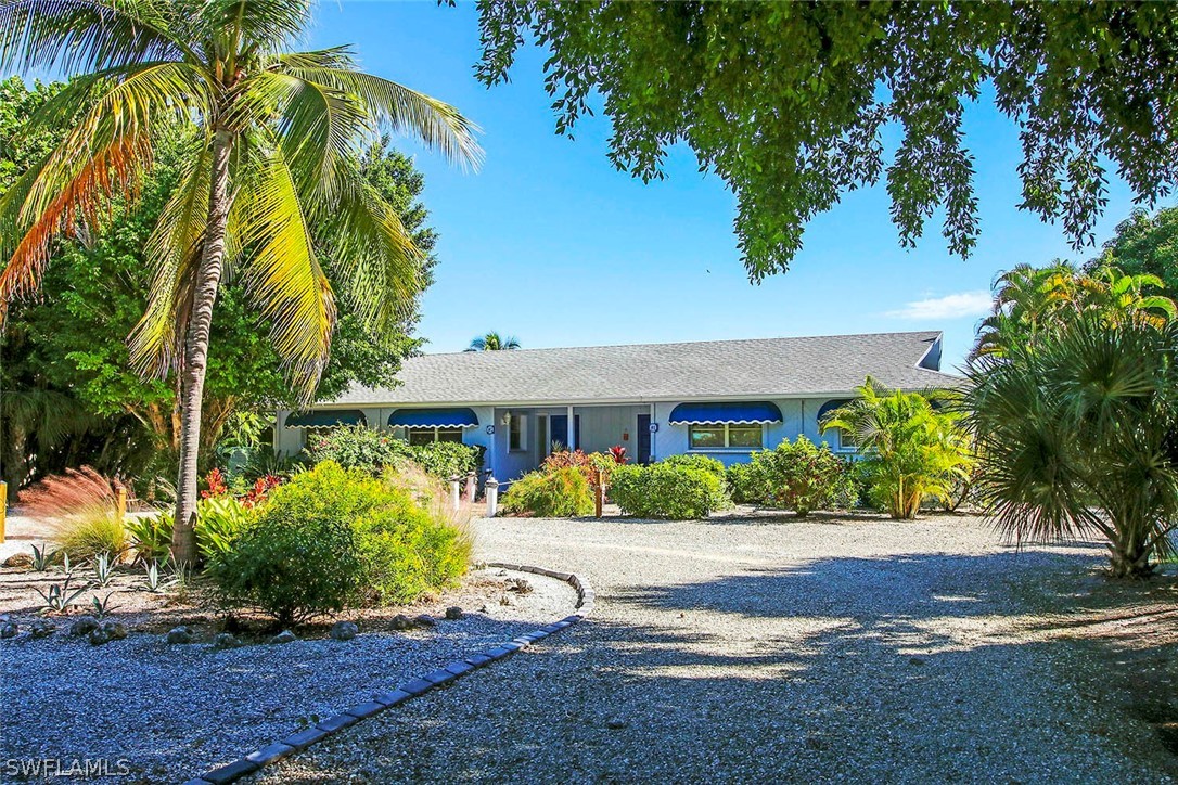 822 Beach Road Sanibel, FL 33957 - Photo 1 of 35 a front view of a house with a yard and a garage