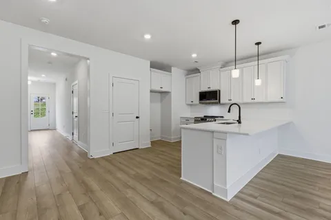 a kitchen with stainless steel appliances granite countertop a refrigerator a sink dishwasher a stove and white countertops with wooden floor