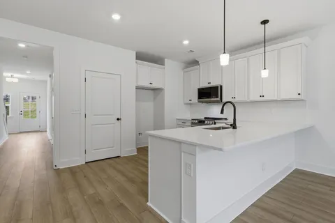 a view of kitchen with stainless steel appliances granite countertop a sink a stove and a wooden floors