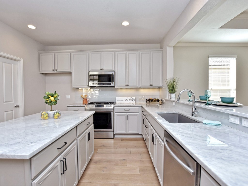 a kitchen with kitchen island granite countertop a sink a counter top space appliances and cabinets