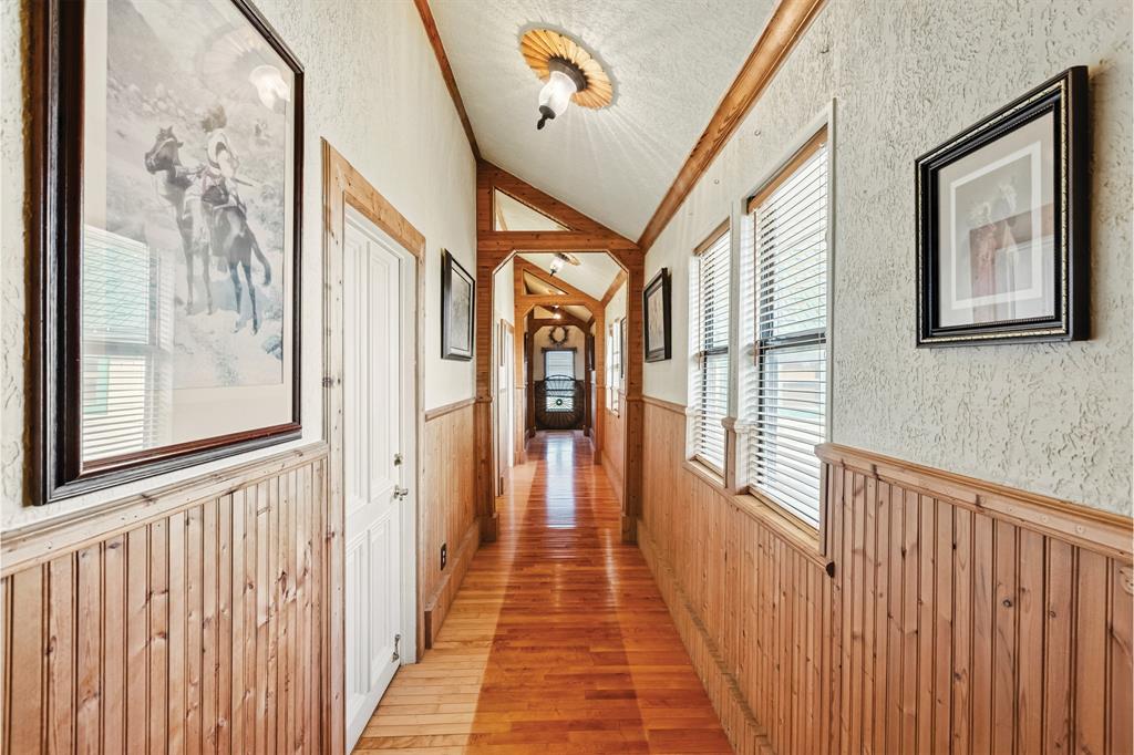 10771 6th Highway Meridian, TX 76665 - Photo 24 of 40 Hallway with a wainscoted wall, wood walls, light wood-type flooring, vaulted ceiling, and a textured ceiling