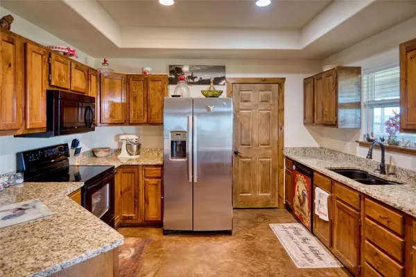 a kitchen with stainless steel appliances granite countertop a refrigerator a stove and a sink