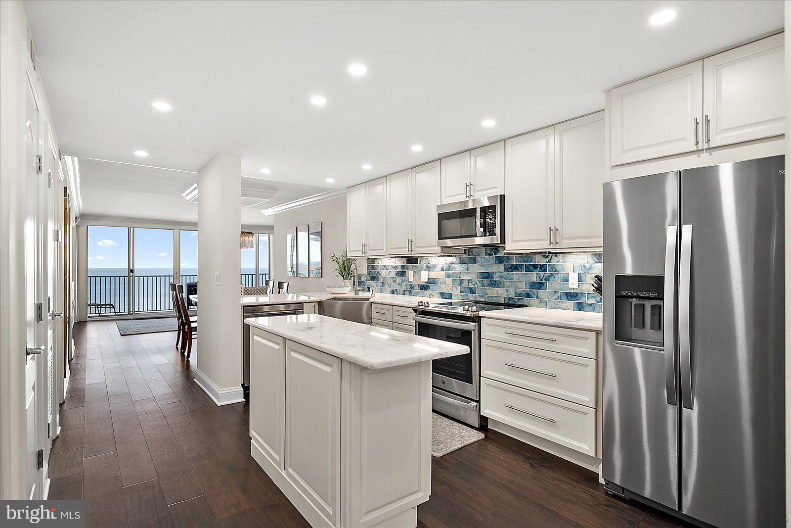903 North Edgewater House Road Bethany Beach, DE 19930 - Photo 5 of 43 a kitchen with white cabinets and stainless steel appliances