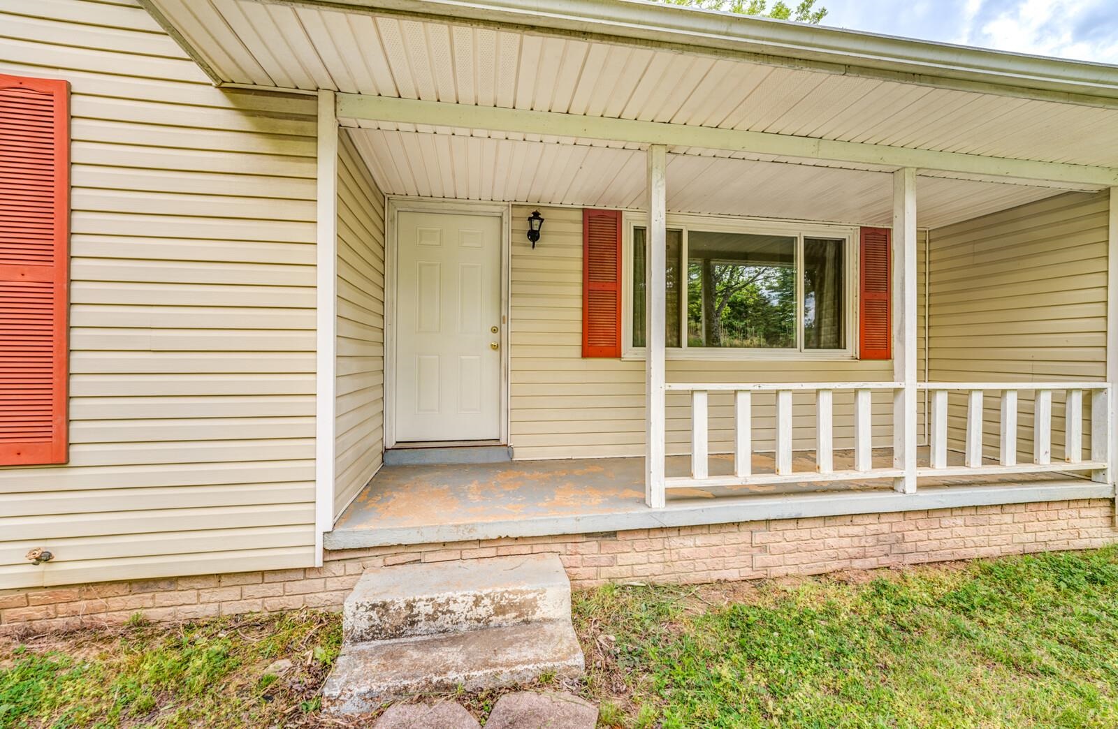 6125 Warren Road Oakland, TN 38060 - Photo 5 of 40 Covered porch entry featuring a paneled door, horizontal siding, and decorative red shutters