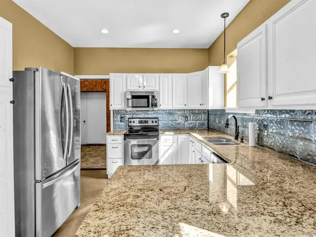 a kitchen with stainless steel appliances granite countertop a refrigerator sink and stove