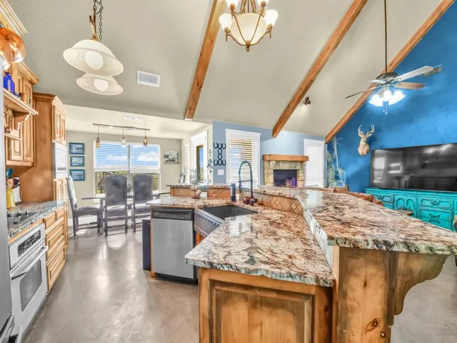 a living room with stainless steel appliances granite countertop furniture wooden floor and a fireplace