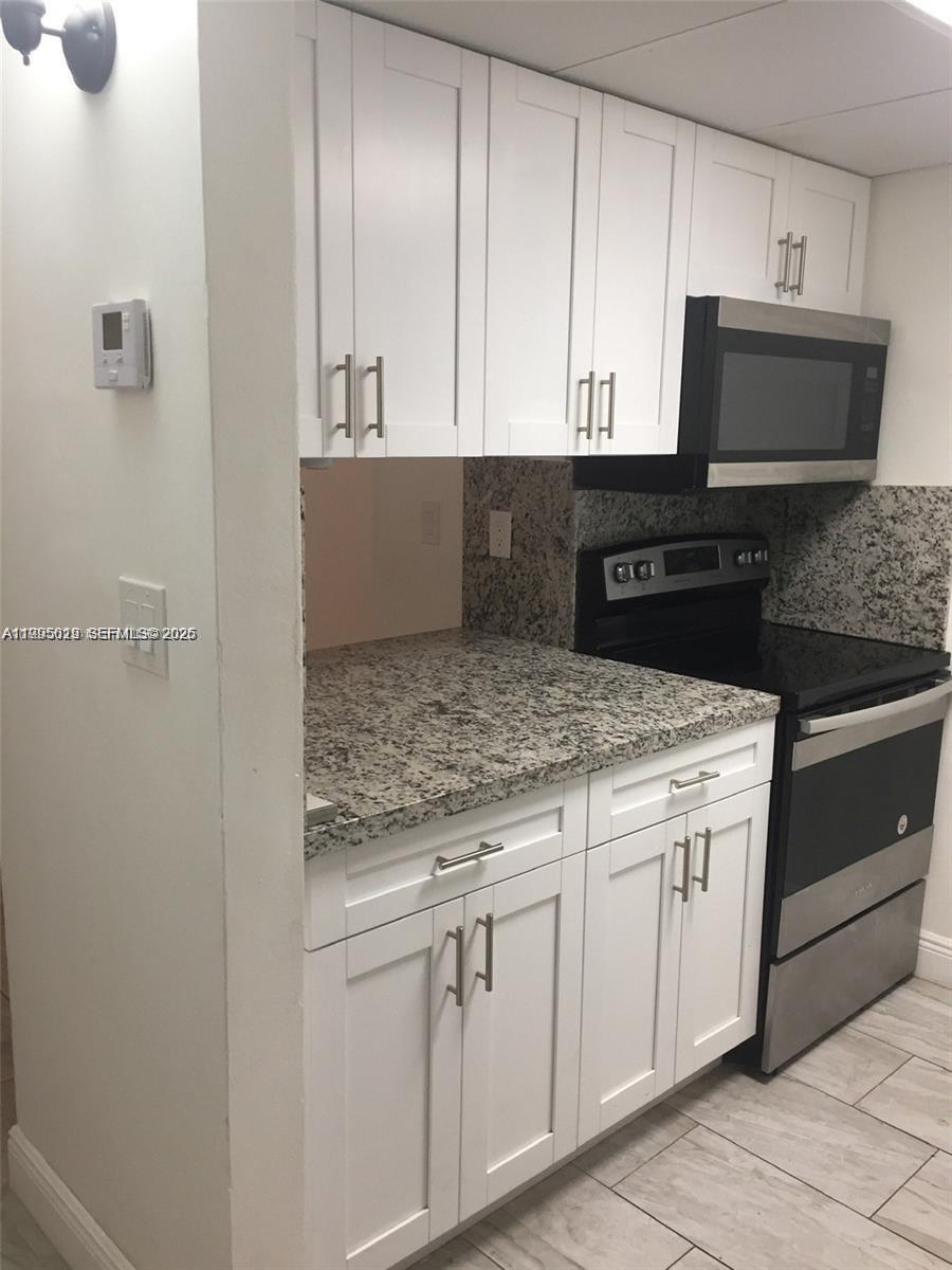 777 Southwest 9th Avenue, Unit 411 Miami, FL 33130 - Photo 1 of 14 a kitchen with white cabinets and black appliances