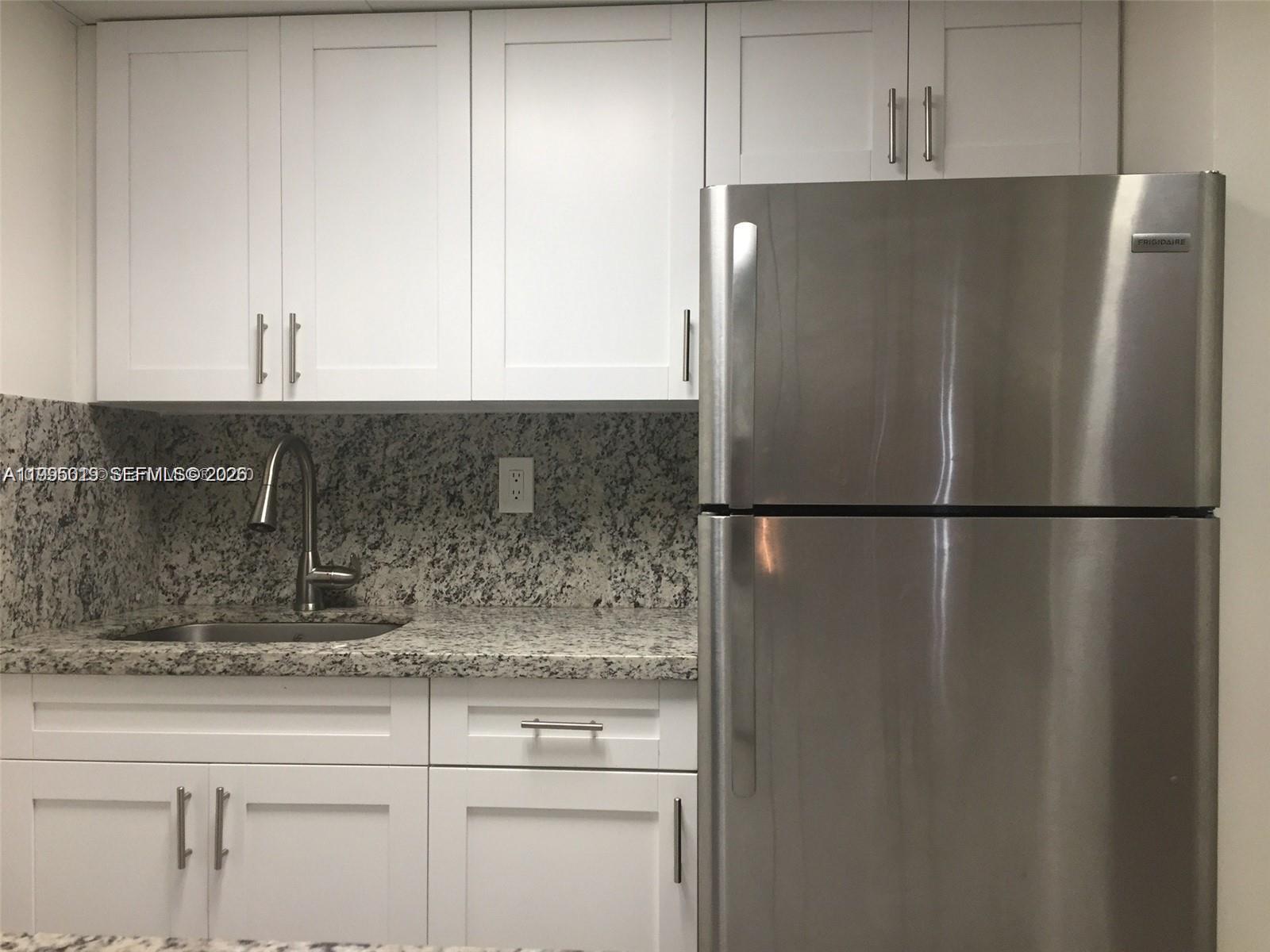 777 Southwest 9th Avenue, Unit 411 Miami, FL 33130 - Photo 4 of 14 a kitchen with a refrigerator and cabinets