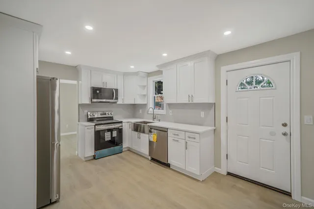 a kitchen with stainless steel appliances granite countertop a stove top oven a sink and dishwasher a refrigerator with wooden floor