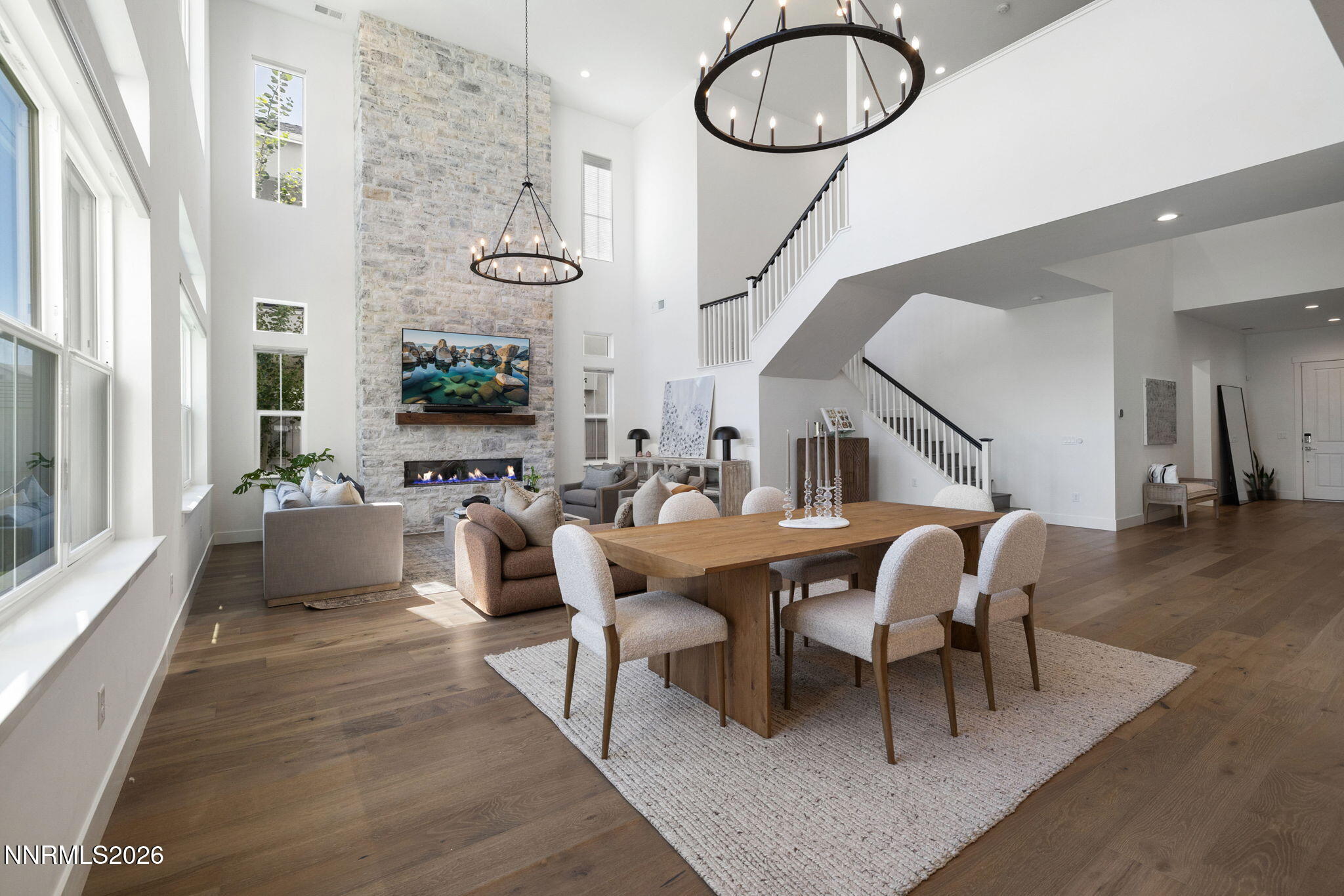 a dining room with wooden floor a chandelier a glass table and chairs