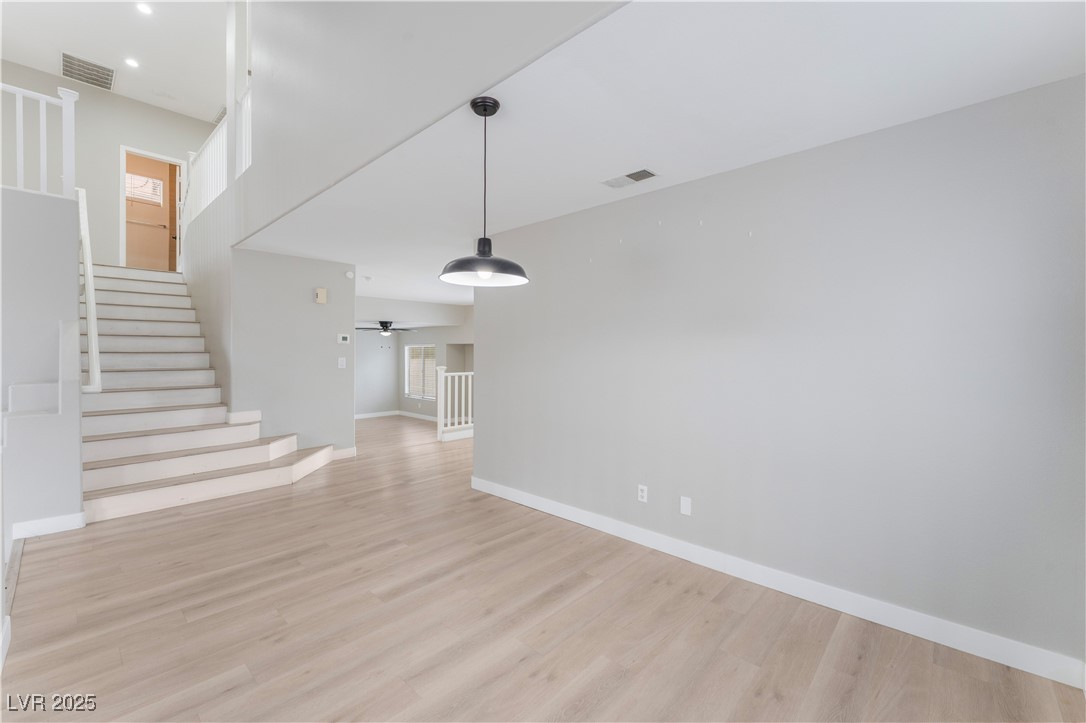 3695 Funston Way Las Vegas, NV 89129 - Photo 12 of 43 Unfurnished living room with stairway, light wood-style flooring, and healthy amount of natural light