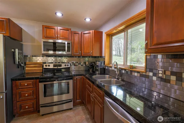a kitchen with stainless steel appliances granite countertop a stove a sink and a microwave