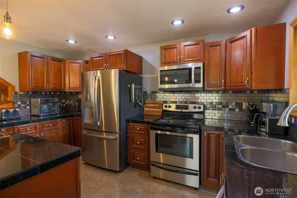 a kitchen with stainless steel appliances granite countertop a stove a refrigerator and a sink