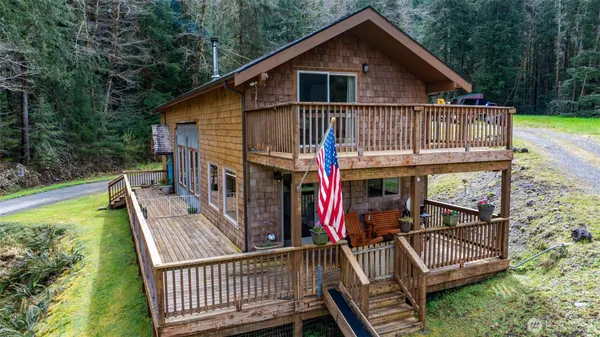 a view of small house with wooden deck and furniture