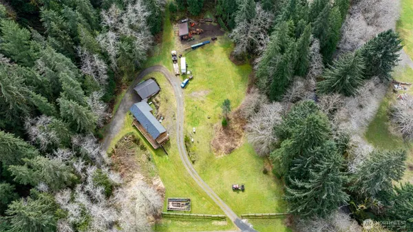 an aerial view of a residential houses with outdoor space and trees all around