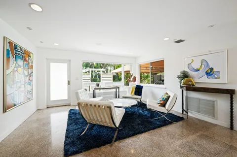 a living room with furniture two window and a flat screen tv