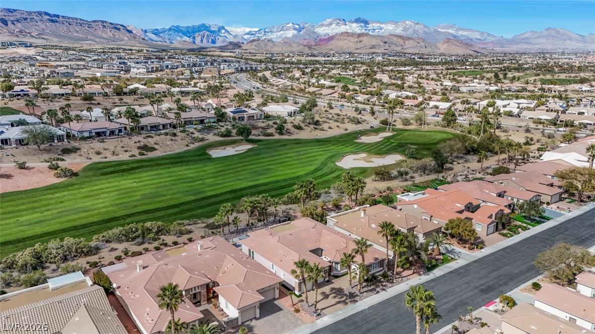 5015 Rivedro Street Las Vegas, NV 89135 - Photo 69 of 91 A vibrant green golf course winds through a desert community, framed by snow-capped mountains and clear skies.