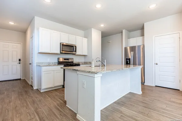 a kitchen with granite countertop a refrigerator stove top oven and sink