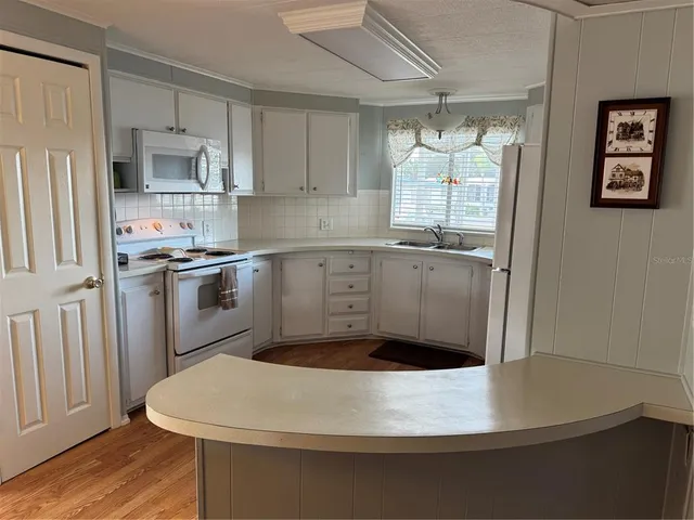 a kitchen with stainless steel appliances a refrigerator sink and wooden floor