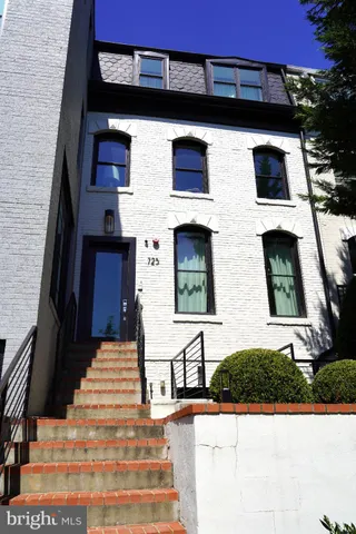 a view of a brick house with windows and palm tree