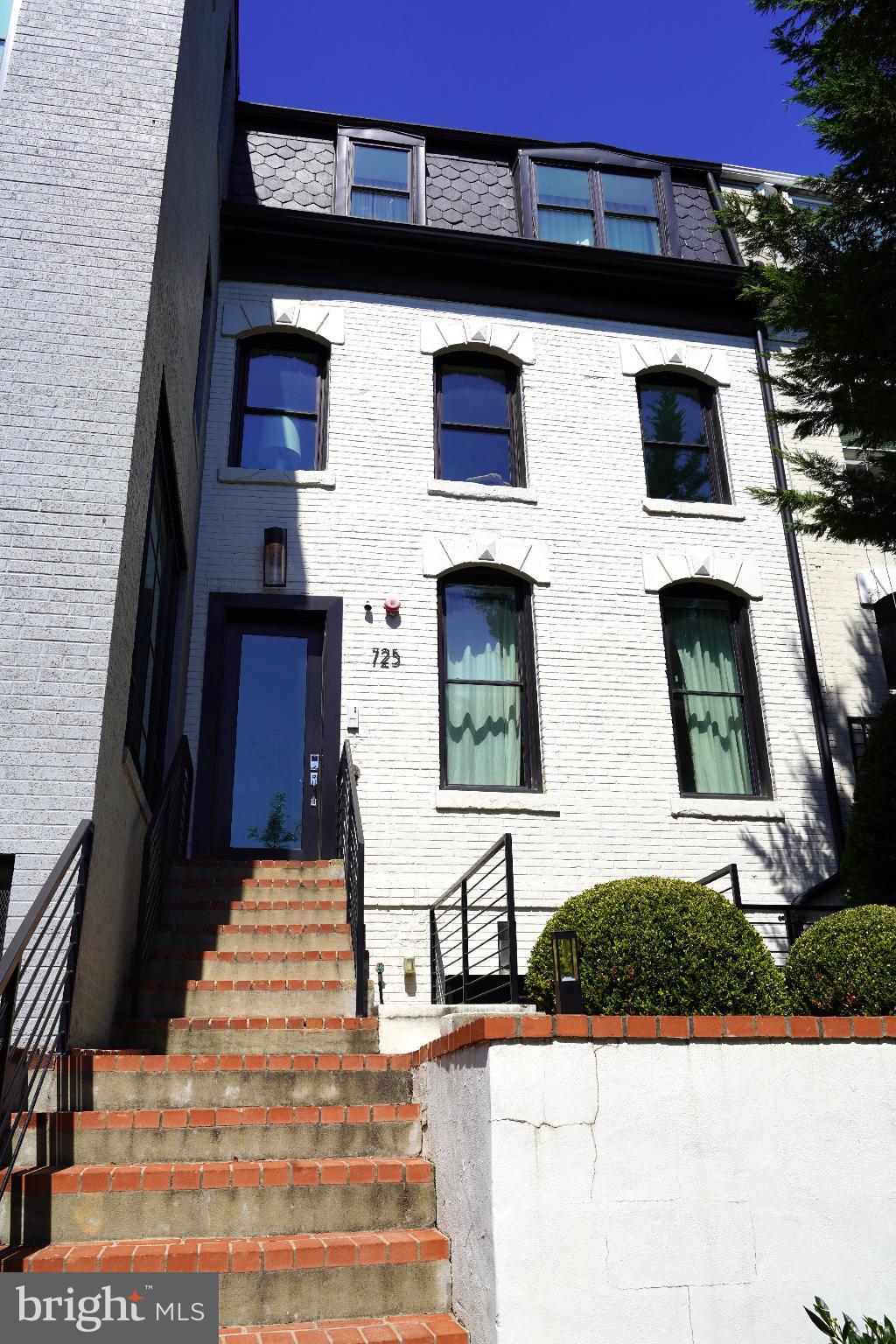 a view of a brick house with windows and palm tree