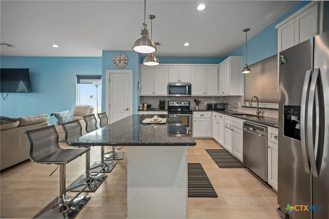 a large kitchen with stainless steel appliances kitchen island granite countertop a refrigerator a stove a sink a dining table and chairs