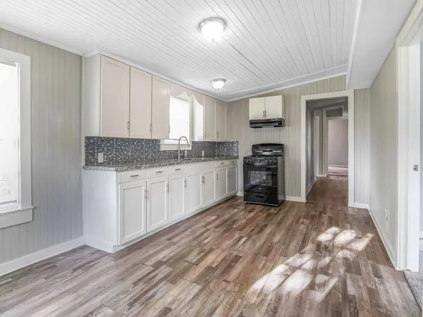 a kitchen with granite countertop a stove a sink and a refrigerator
