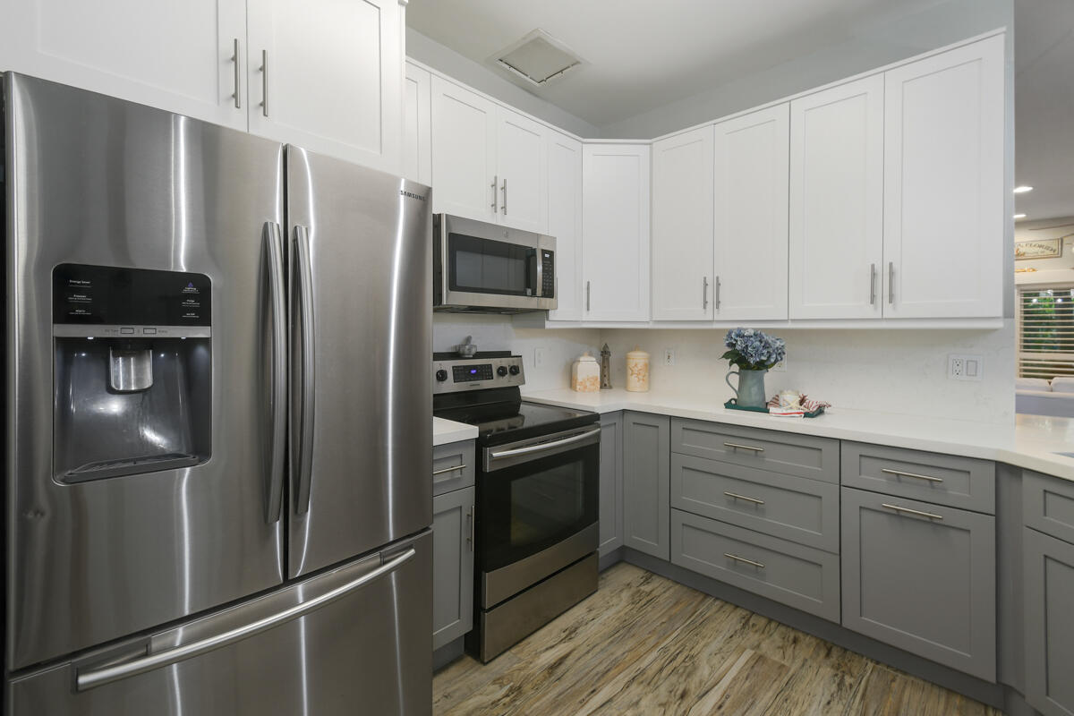 105 Lighthouse Circle, Unit D Tequesta, FL 33469 - Photo 9 of 36 a kitchen with stainless steel appliances and wooden cabinets