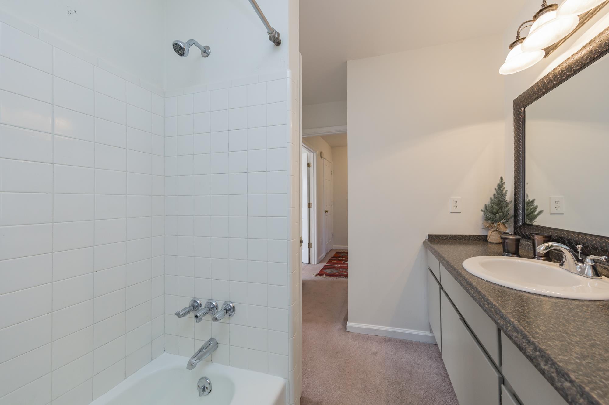 765 Kent Road, Unit 765 Nashville, TN 37214 - Photo 22 of 30 a bathroom with a granite countertop sink a mirror and a bathtub