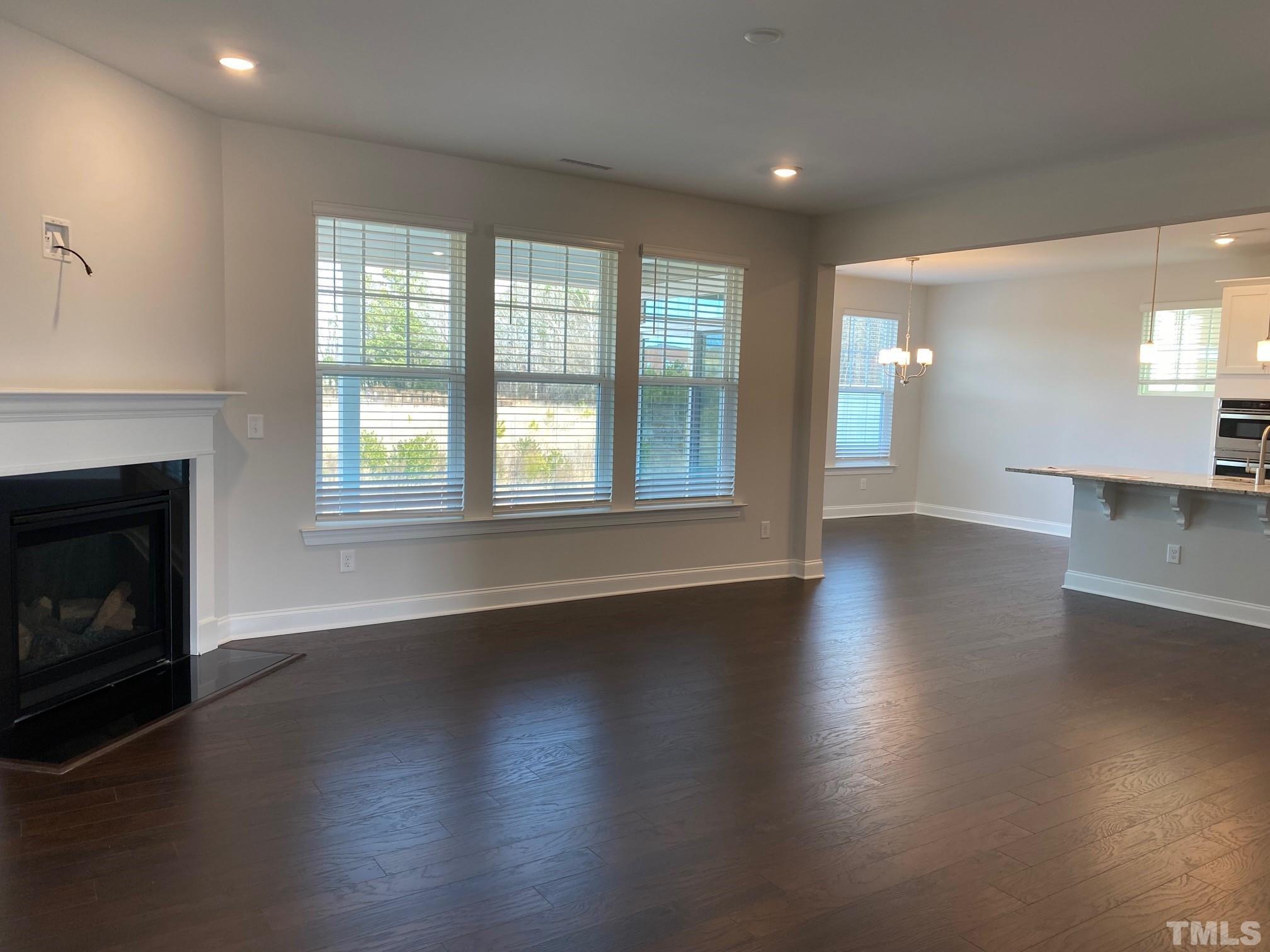 312 Ressler Street, Unit 504 Holly Springs, NC 27540 - Photo 4 of 30 an empty room with wooden floor and a fireplace