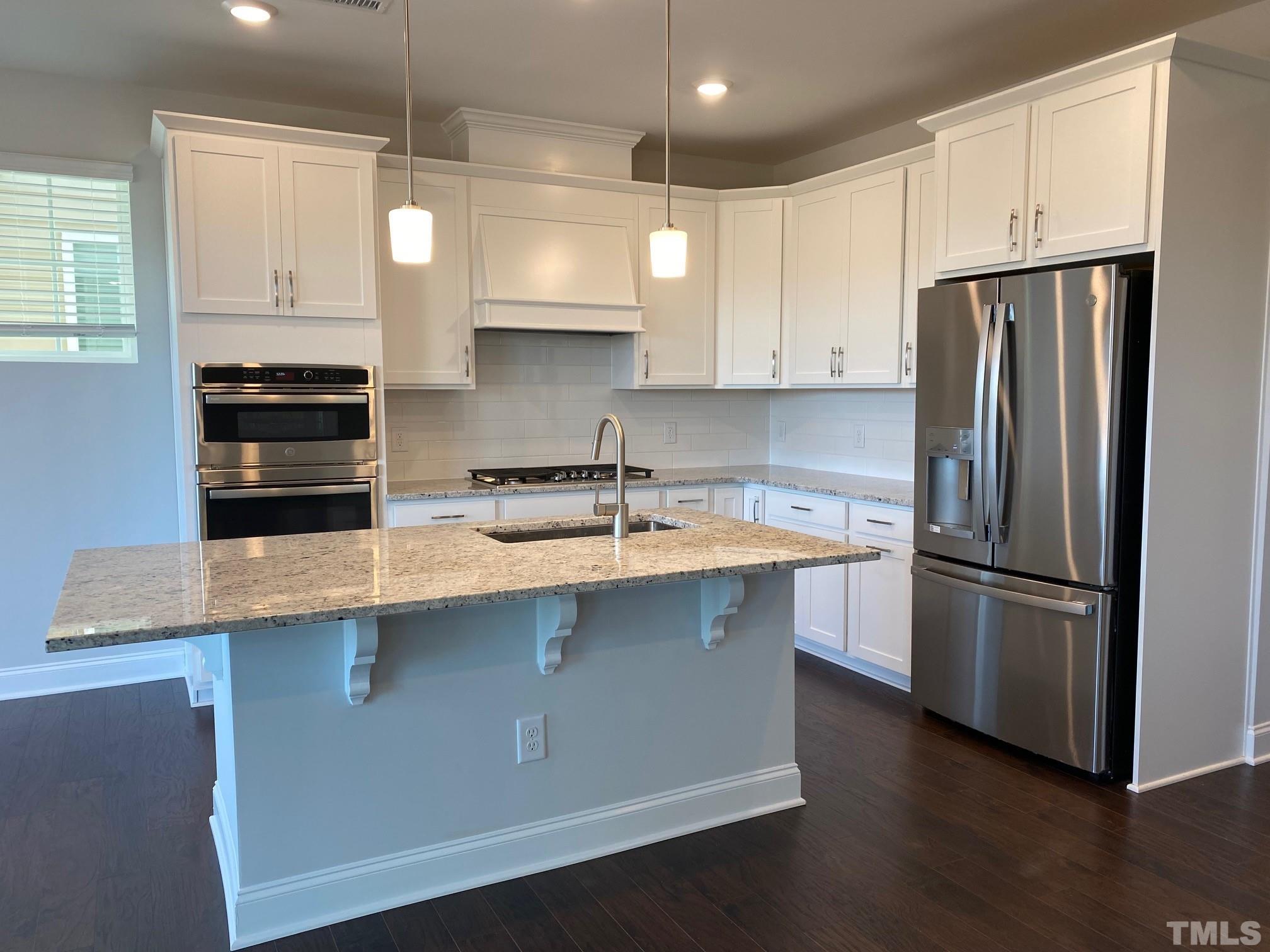 312 Ressler Street, Unit 504 Holly Springs, NC 27540 - Photo 6 of 30 a kitchen with stainless steel appliances a sink a stove a refrigerator and white cabinets