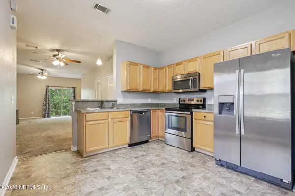 a kitchen with stainless steel appliances granite countertop a refrigerator a stove a sink and a microwave