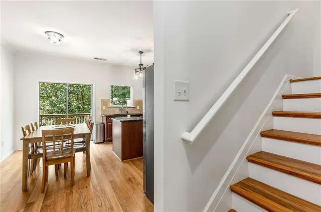 a kitchen with stainless steel appliances granite countertop a stove a refrigerator a kitchen island a sink dishwasher a dining table and chairs with wooden floor