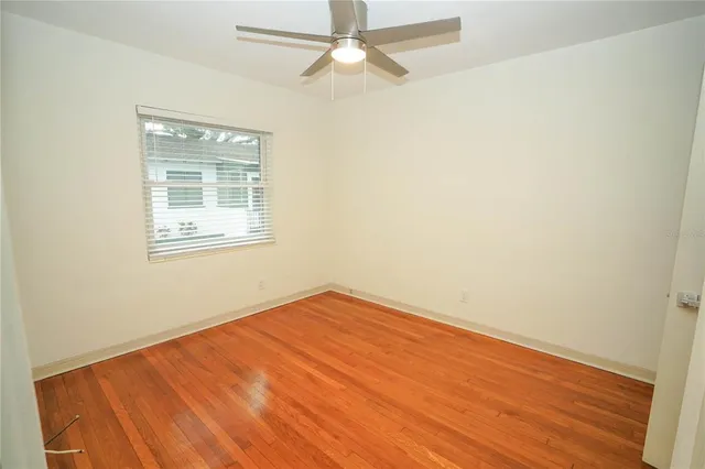 an empty room with a window and ceiling fan
