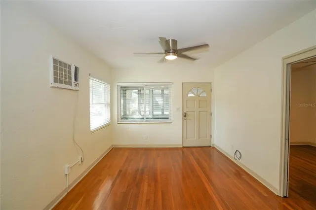 a view of empty room with wooden floor and fan
