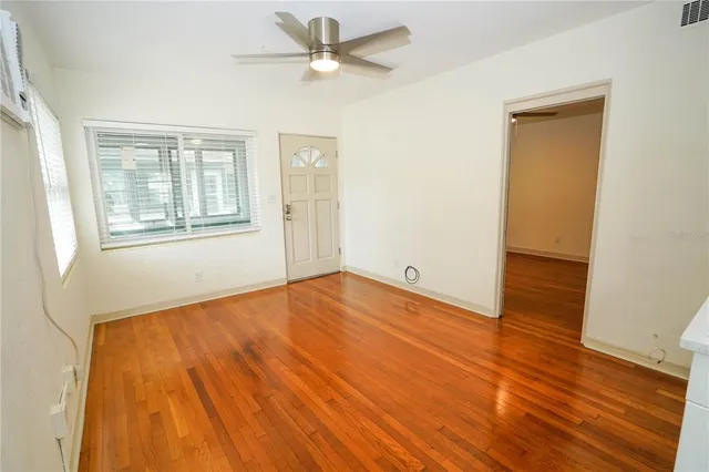 a view of empty room with wooden floor and fan