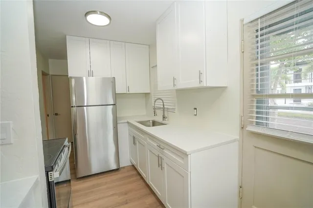 a kitchen with a refrigerator a stove a sink and a window