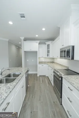a large kitchen with a granite countertop sink stainless steel appliances and white cabinets