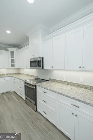 a kitchen with granite countertop white cabinets and white appliances