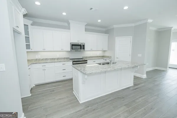 a kitchen with stainless steel appliances white cabinets a sink and a stove