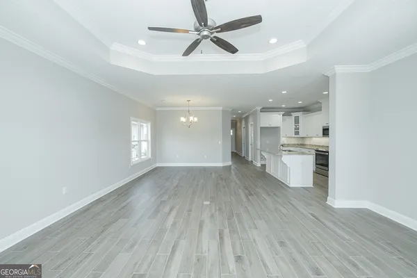 a view of kitchen and empty room with wooden floor