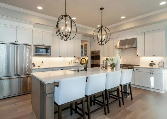 a kitchen with stainless steel appliances a table chairs refrigerator and cabinets