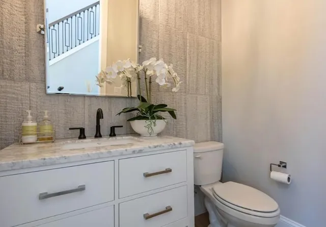 a bathroom with a granite countertop sink mirror vanity and toilet