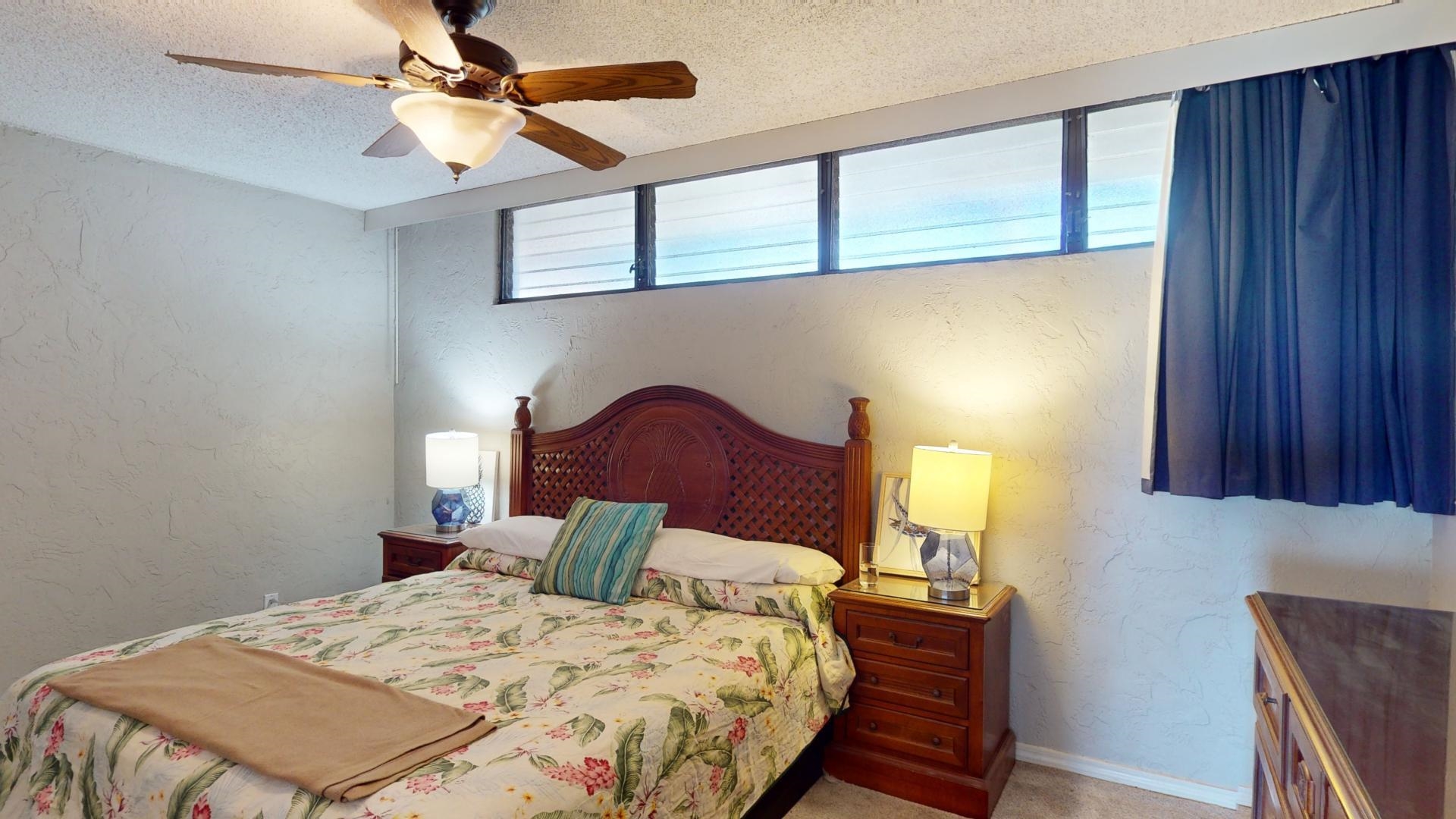 3543 Lower Honoapiilani Road, Unit A107 Lahaina, HI 96761 - Photo 13 of 19 a bedroom with a bed a dresser and potted plants with the wooden floor