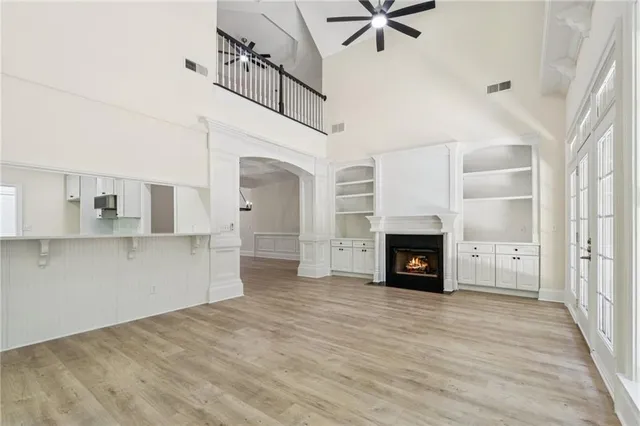 a view of a livingroom with a fireplace a ceiling fan and windows