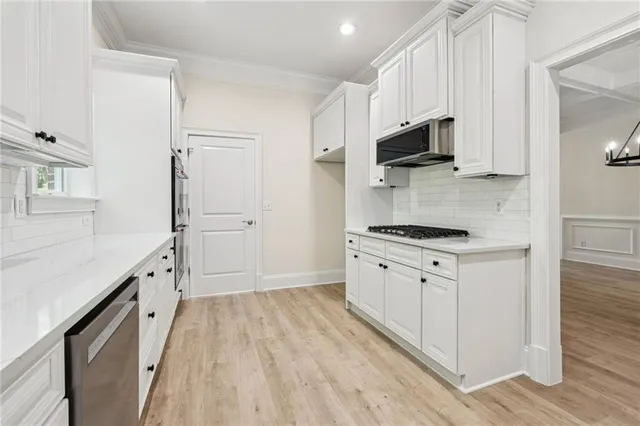 a kitchen with granite countertop white cabinets and stainless steel appliances