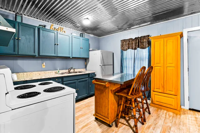 a kitchen with stainless steel appliances granite countertop a stove a sink dishwasher and a refrigerator with wooden cabinets