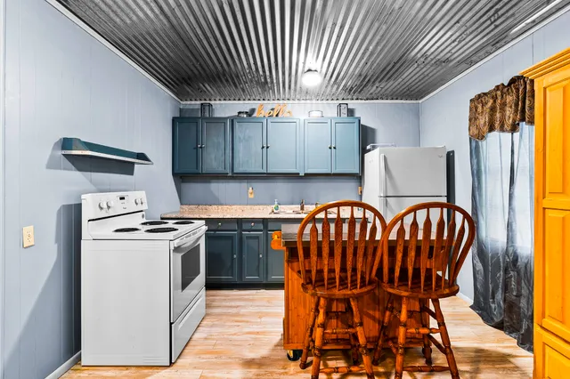 a kitchen with stainless steel appliances granite countertop a stove a refrigerator a dining table and chairs with wooden floor