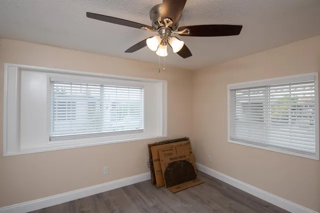 a room with chandelier fan and windows