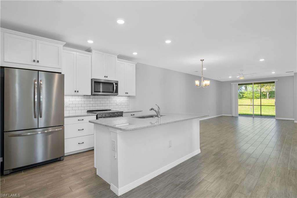 14559 Edgewater Circle Naples, FL 34114 - Photo 5 of 49 a kitchen with stainless steel appliances granite countertop a refrigerator a sink dishwasher a stove and white cabinets with wooden floor